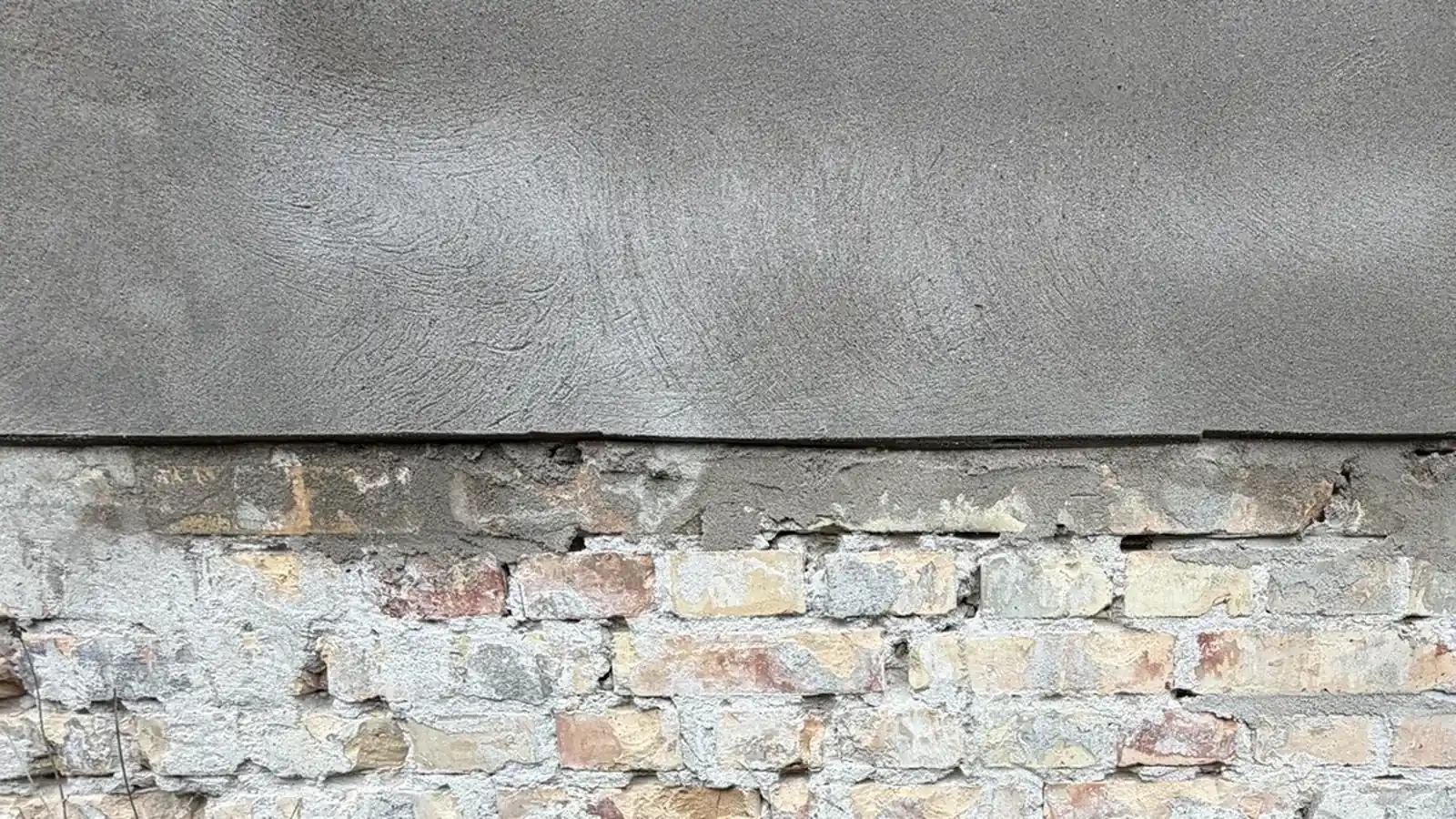 Pudset facade med synligt ældre murværk og mørtelfuger.
